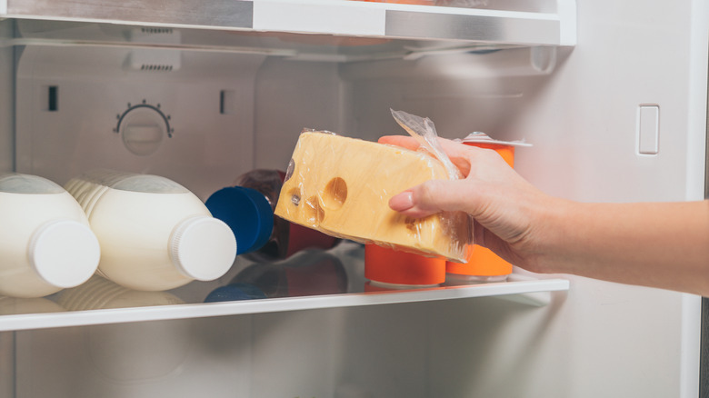 Hand removing cheese from fridge