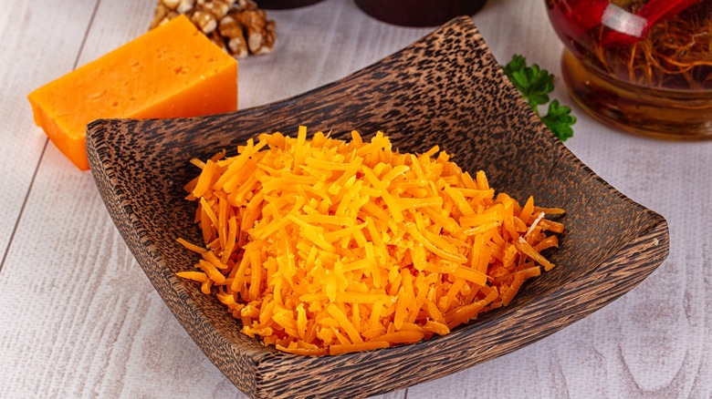 Shredded cheddar cheese in wood bowl