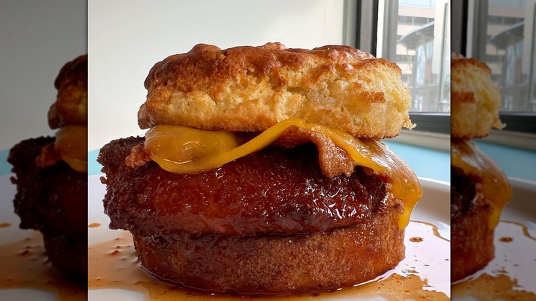 Dutch´s crispy chicken biscuit with bacon and cheddar on a plate doused in syrup