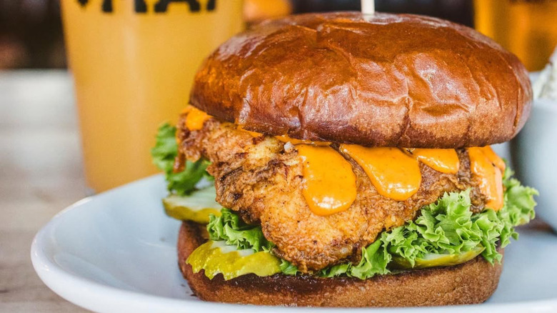 MAP Brewing Company fried chicken sandwich on a white plate, pint of beer in the background