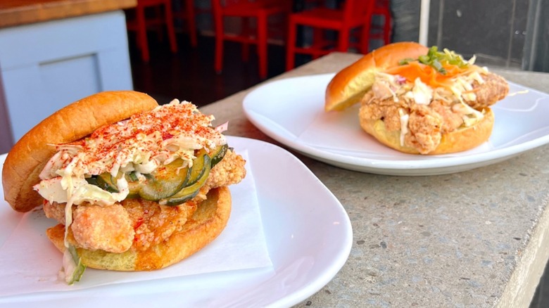 two Spicy Chicken Sandos on white plates at Nanban