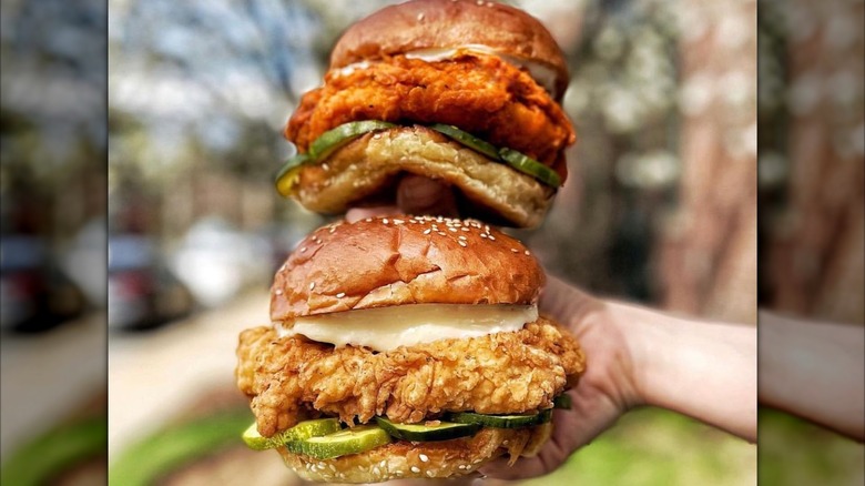 close up of a hand holding a Honeybird OG and Spicy Chicken Sandwiches