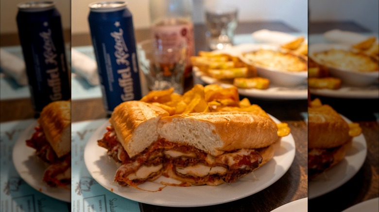 Berkeley's Chicken Parm Sandwich plated with fries on a table, more food in the background