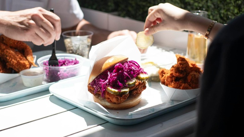 Close up of a tableat Pretty Bird, one diner about to eat a Fried Chicken Sandwich