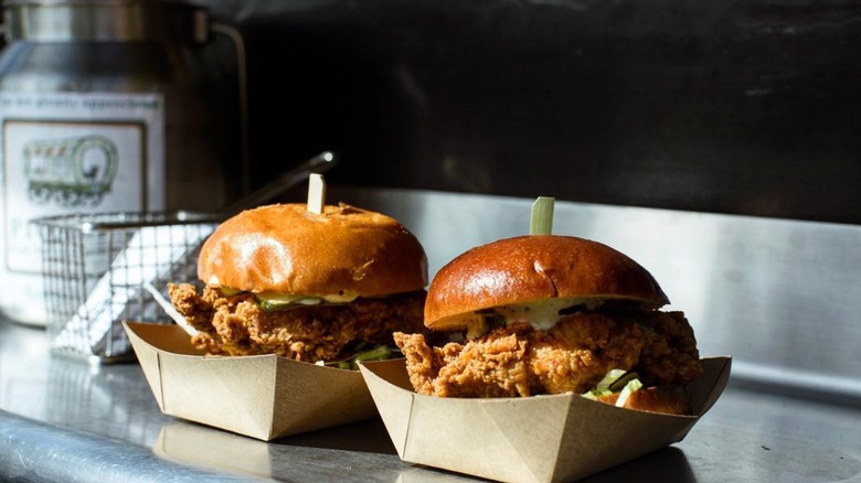2 Pioneer Lakeshore Cafe Crispy Chicken Sandwiches awaiting pickup on a stainless steel counter