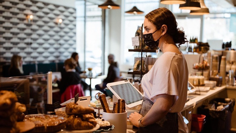 interior of picnic, barista working behind the counter with pastries on display