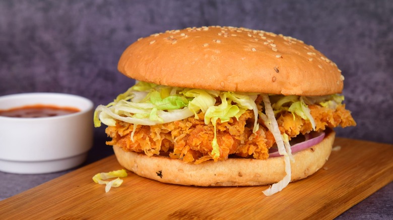 Fried chicken sandwich with lettuce and onions on sesame seed bun