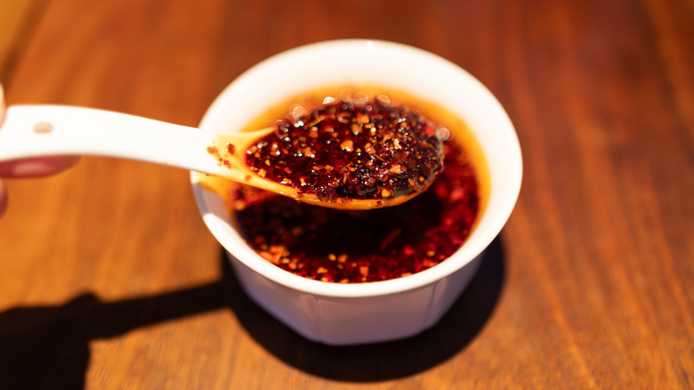 Chili crisp oil in a white bowl with white spoon