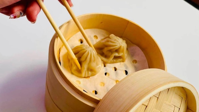 Hand picking up a dumpling with chopsticks at Huang's Noodle Shop.