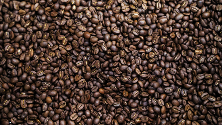Dark roasted coffee beans spread out in a pile