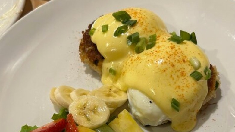 Crab Cake Benedict with side of Fresh Fruit on a white plate at Red Spire Brunch House