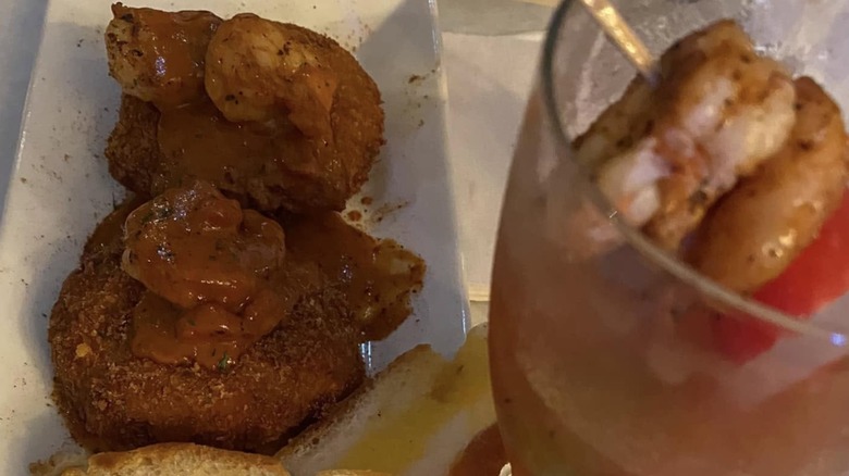 Crab Cakes topped with shrimp on a rectangular white plate at Blu Jazz Cafe
