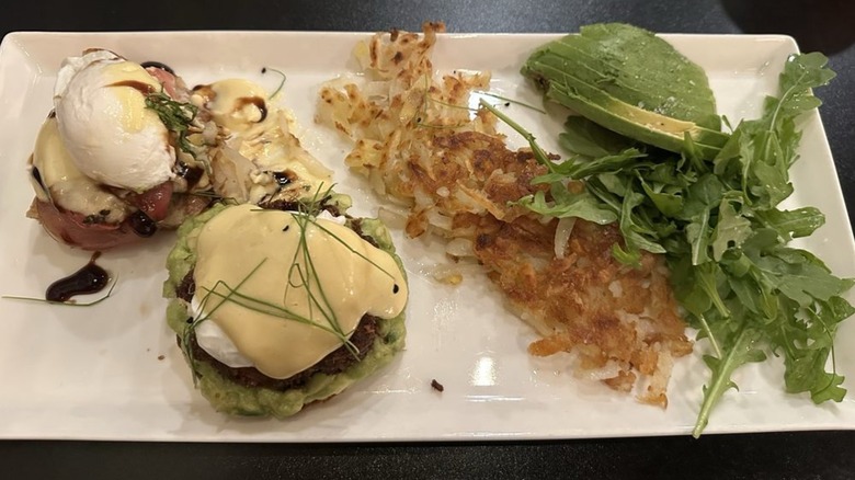 Mixed Bennie plate including Crab Cake Benedict, hash browns, arugula, and side of avocado sliced at Jam!