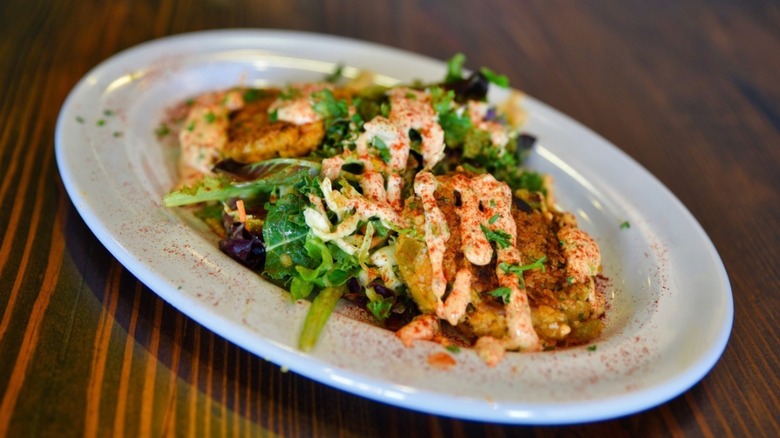 Plate of Crab Cakes ver greens with a remoulade sauce at Acadian Grille & Bar