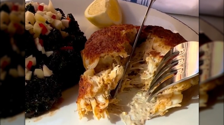 Hand seen cutting into Crab Cake at Oyster House