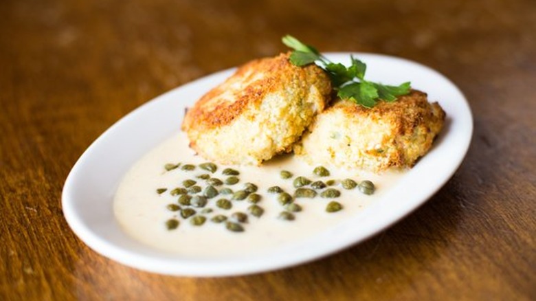 Crab cakes with caper sauce and parsley garnish on a white plate at Kells Irish Restaurant & Pub