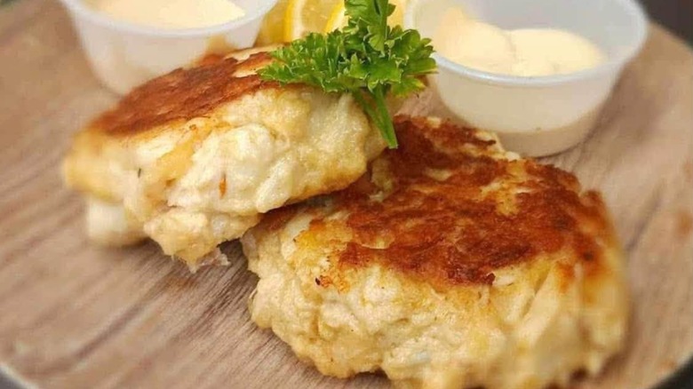 Crab cakes with mayo and fresh herbs on wooden plate at Long Point Grille & Bar 