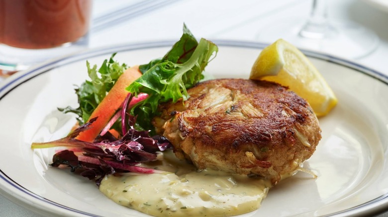Maryland-Style Crab Cake with garnish of fresh greens and sliced lemon on a white plate at Harbor House