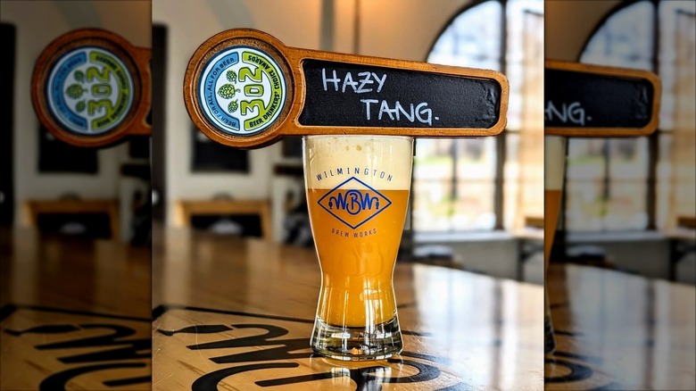 Beer glass with beer name, Hazy Tang, written on tap dispenser