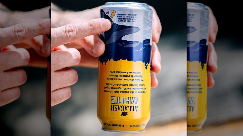 hand holding can of allagash white beer upside down