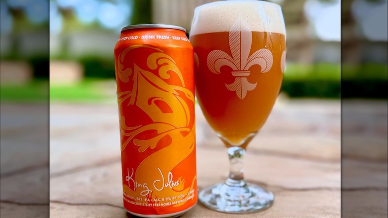 An orange tallboy beer next to a beer glass of orange beer
