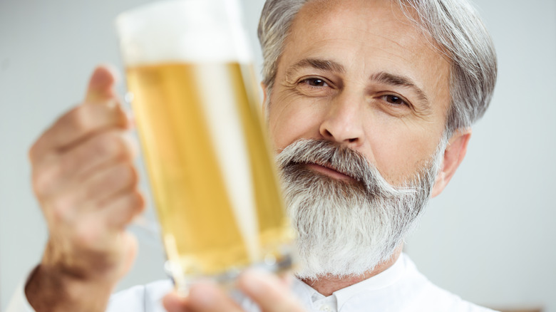 Gray-haired man smiling and holding a pint of beer