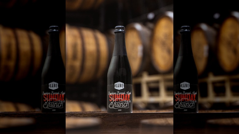 Sunday Brunch black beer bottle against background of barrels