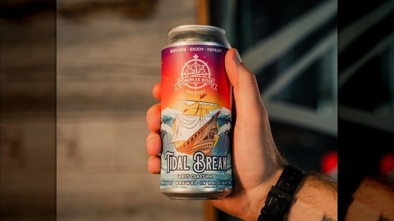Hand holds Tidal Break beer can with image of ship