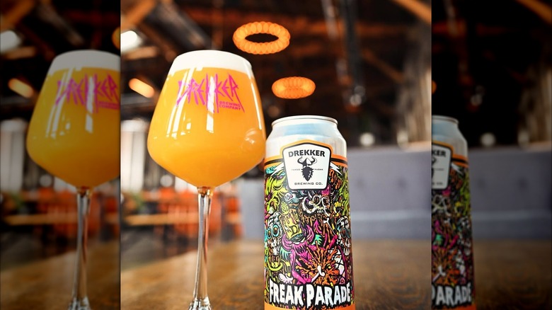 Freak Parade tallboy beer can next to full beer glass with bar in background