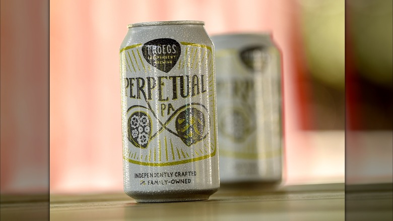 Two Perpetual IPA beer cans on wooden surface