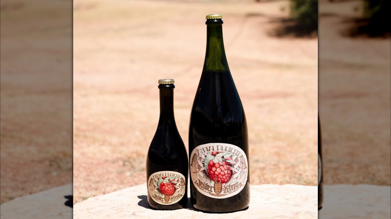 One big beer bottle of Atrial Rubicite next to a smaller on outdoor table