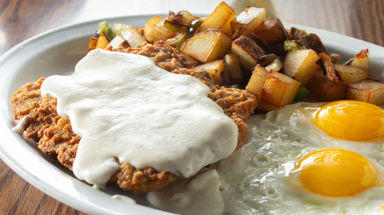 Chicken fried steak with cream gravy, home fries, and sunny side up eggs