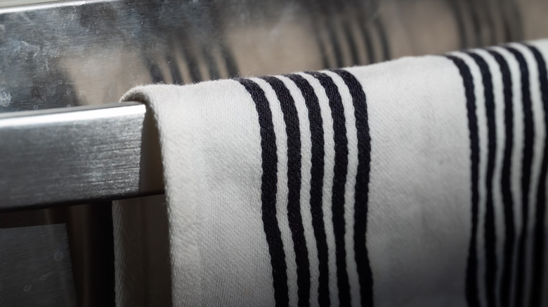 A striped linen dishtowel hung over a metal bar