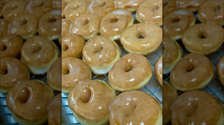 Over a dozen glazed donuts on a metal wire rack