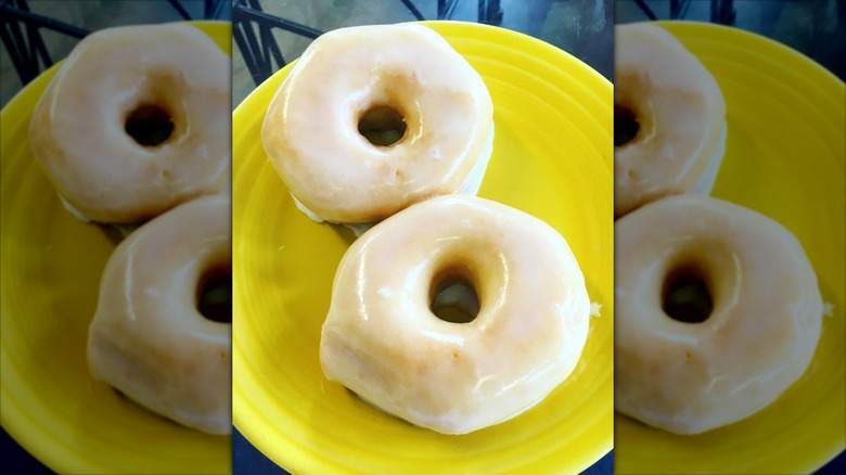 Two glazed donuts on a yellow plate