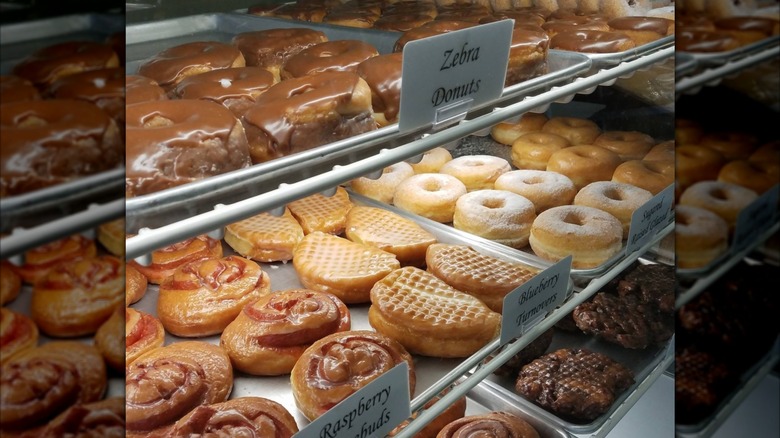 Zebra donuts, turnovers, and raspberry donuts on display in glass case