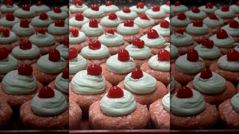 Strawberry colored donuts with frosting and cherry