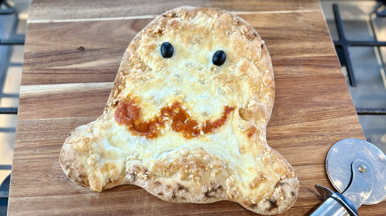 A baked Aldi Halloween ghost pizza on a cutting board