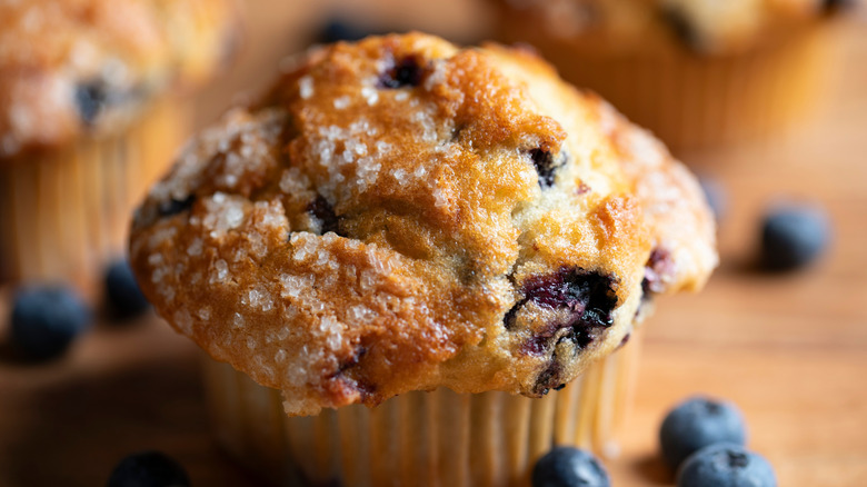 A close-up shot of a blueberry muffin with fresh blueberries