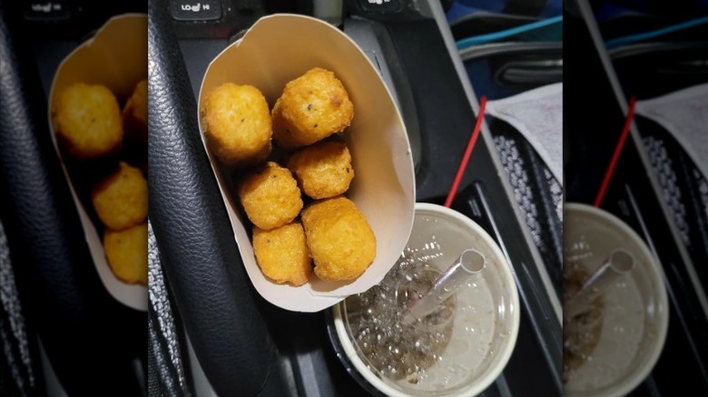 A container of mozzarella sticks from Arby's sitting in a car's cup holder
