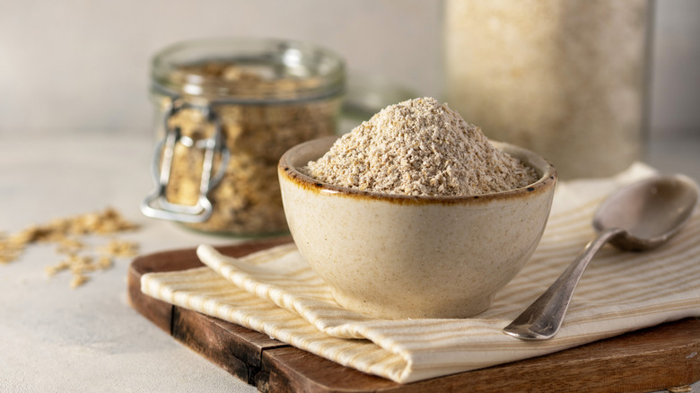 Oat flour in a small beige bowl with a spoon beside it