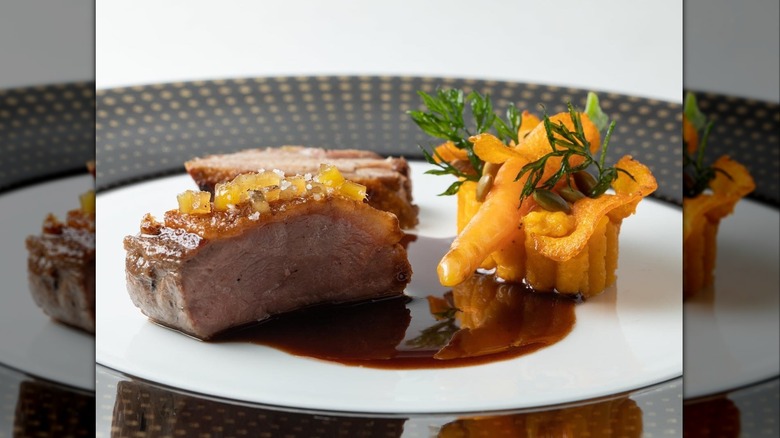 Sliced meat next to unidentifiable orange dish on white plate