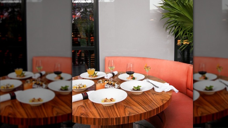 Round wooden table with plates of food and glasses of wine