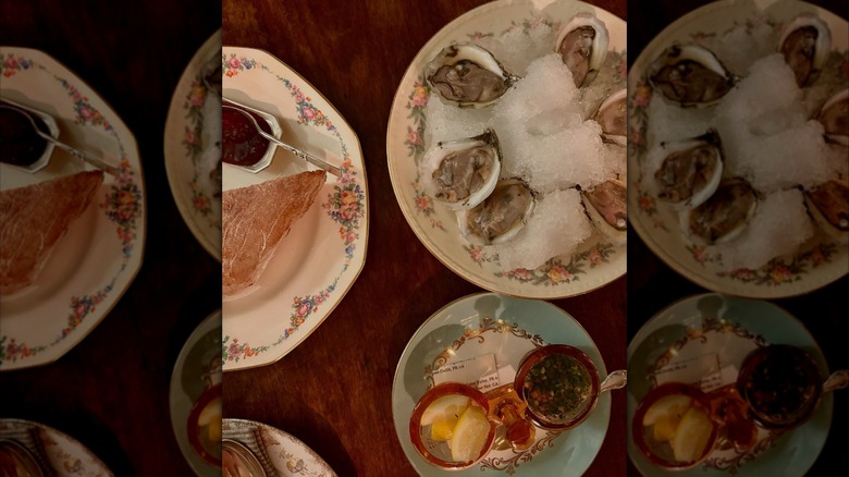 Oysters, bread, lemon wedges and condiments on wooden table