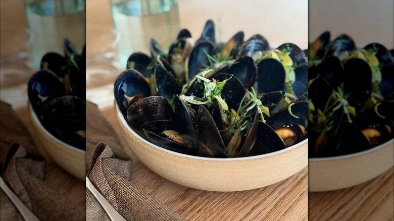 Bowl of mussels with greens on top