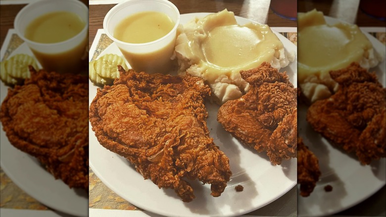 Wishbone fried chicken with sides of mashed potatoes, gravy dipping sauce, and pickles