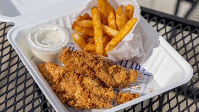 Charlotte's Kitchen Fried Chicken takeaway box with fries and a side of dressing sauce