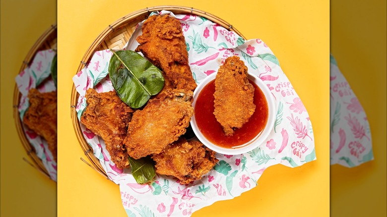 Crispy Gài fried chicken with side of dipping sauce and bright yellow background