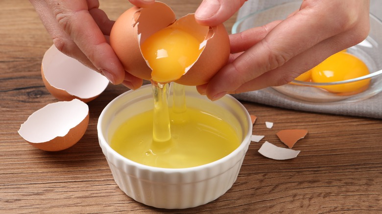 hands using eggshells to separate an egg