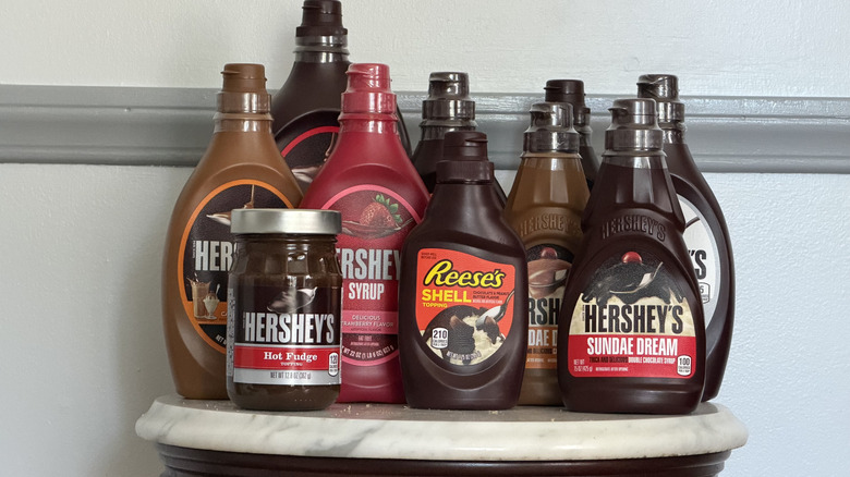 Lineup of Hershey's chocolate sauces against wall.